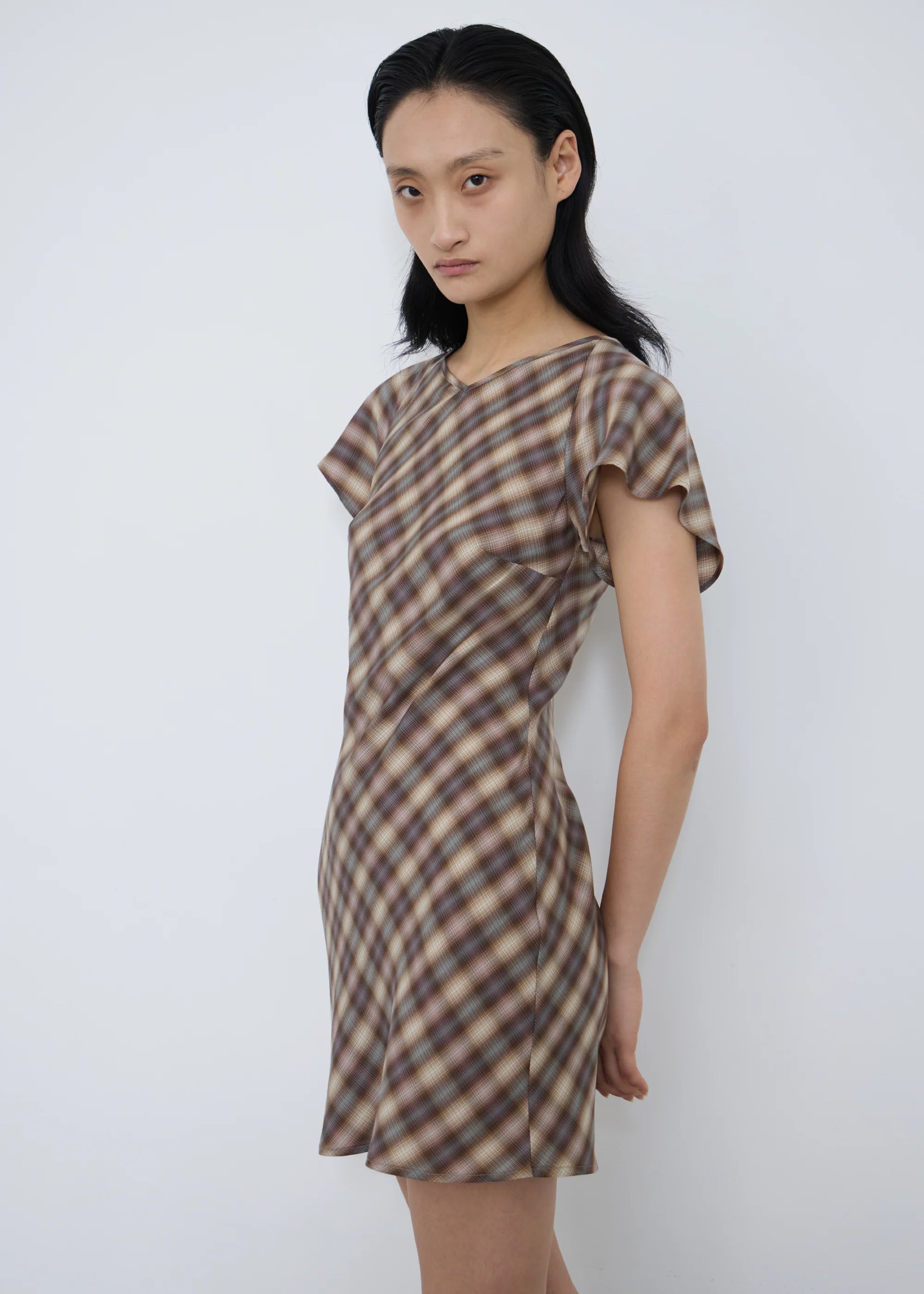 Woman wearing a plaid permanent vacation enmesh mini dress against a white background