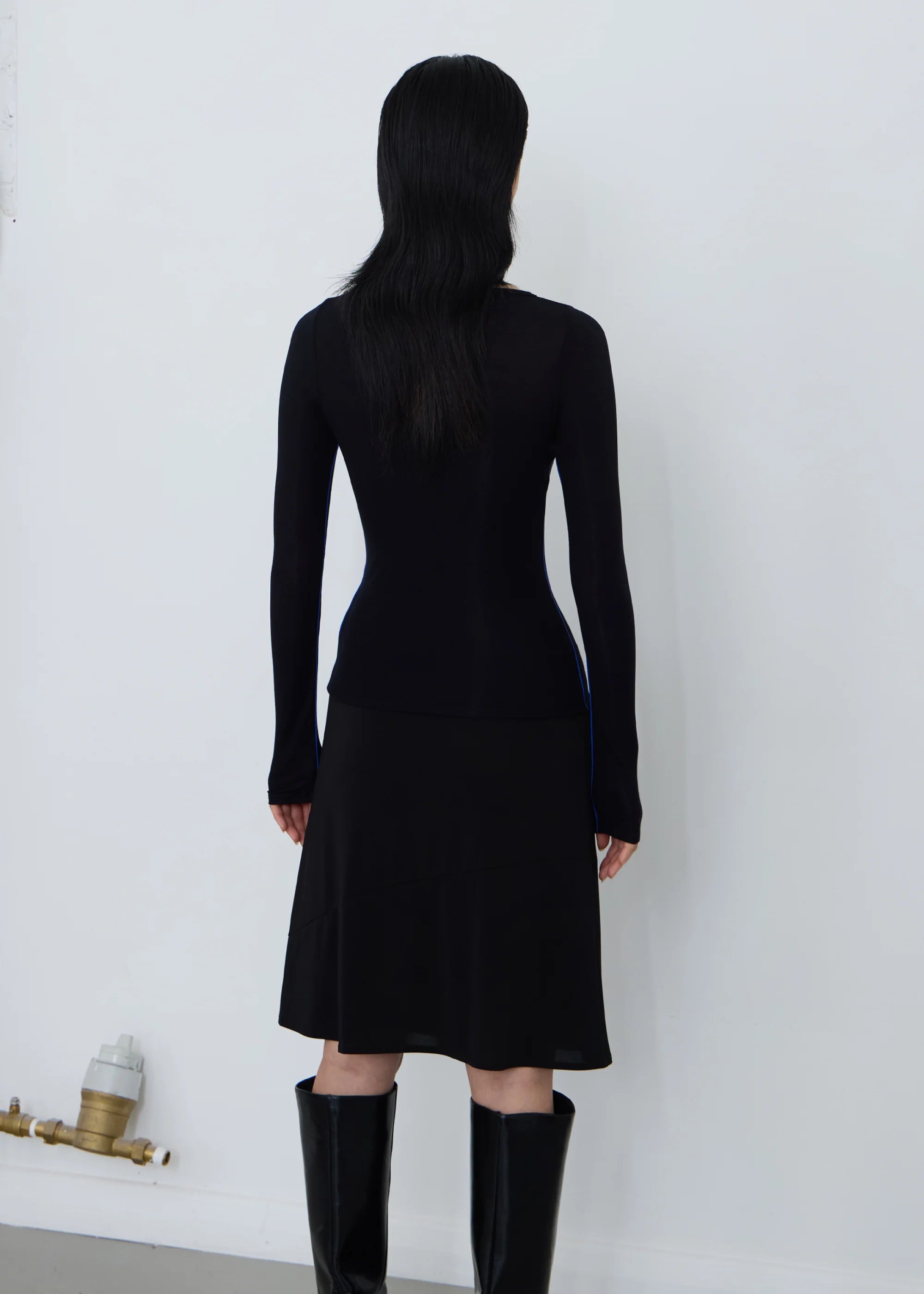 Person wearing a black permanent vacation orbit long-sleeve top with blue accents with a permanent vacation black debut skirt on a white background and long boots