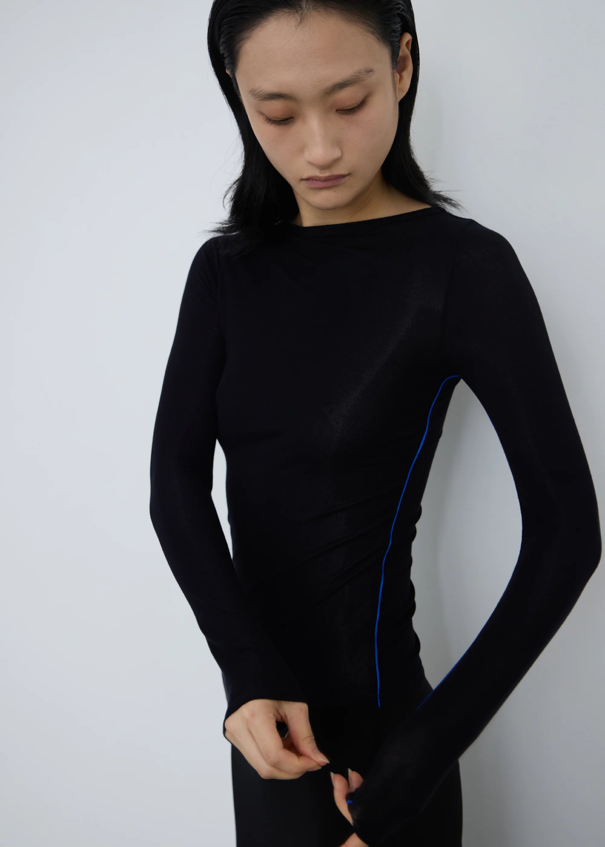 Person wearing a black long-sleeve permanent vacation orbit top against a plain background